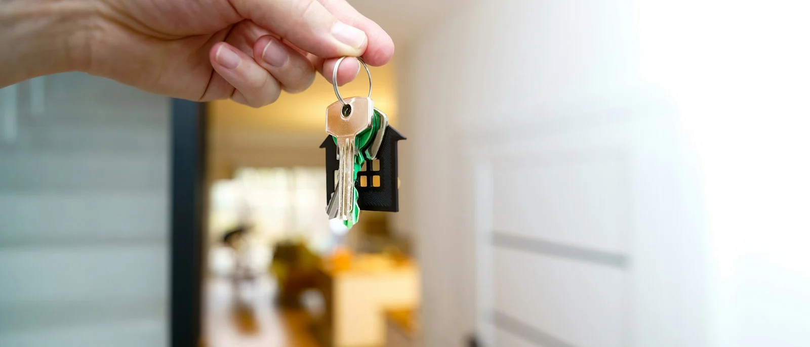 Llaves de una casa en la mano frente a la vivienda